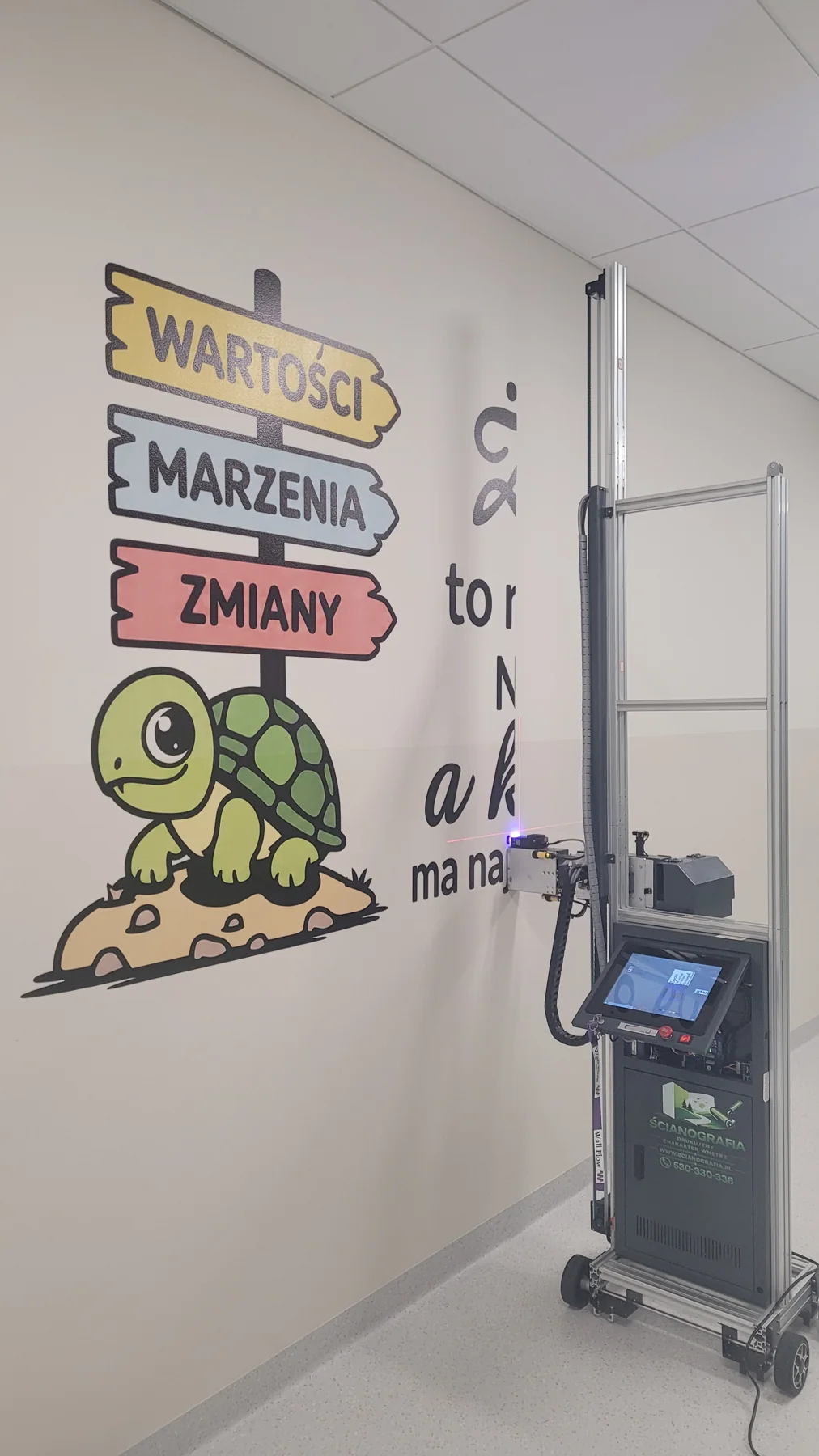 Drukarka ścienna UV podczas wykonywania grafiki Żółw i drogowskazy w szkole w Kłoczewie
